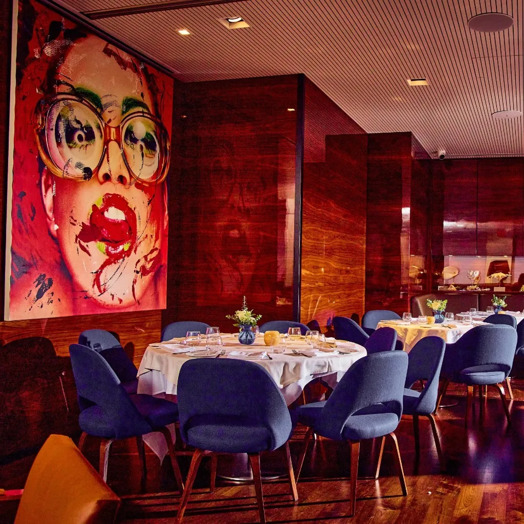 A restaurant dining room with a large portrait and tables set for guests